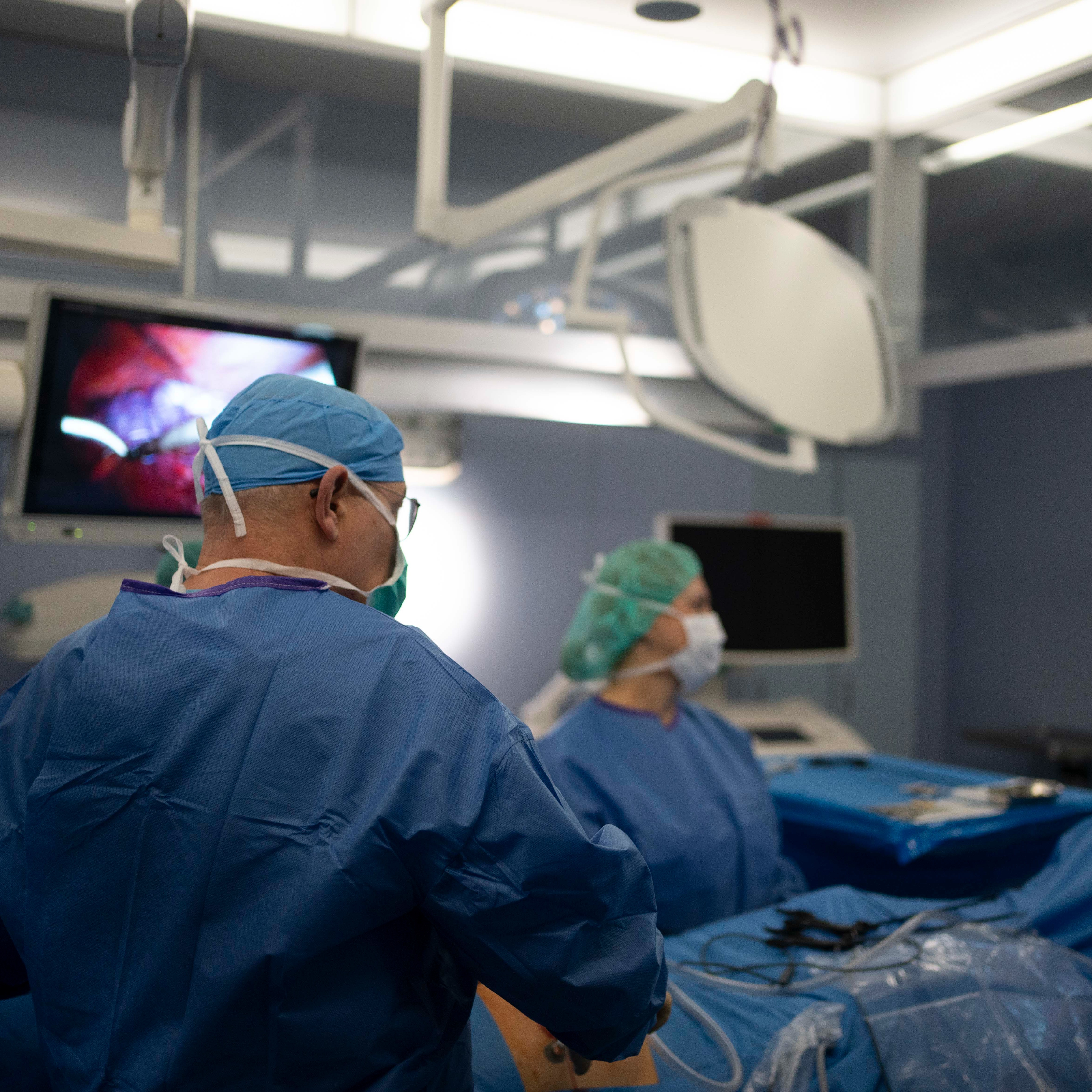 Mehrere medizinische Fachkräfte stehen um ein Krankenhausbett im laufendem OP.
