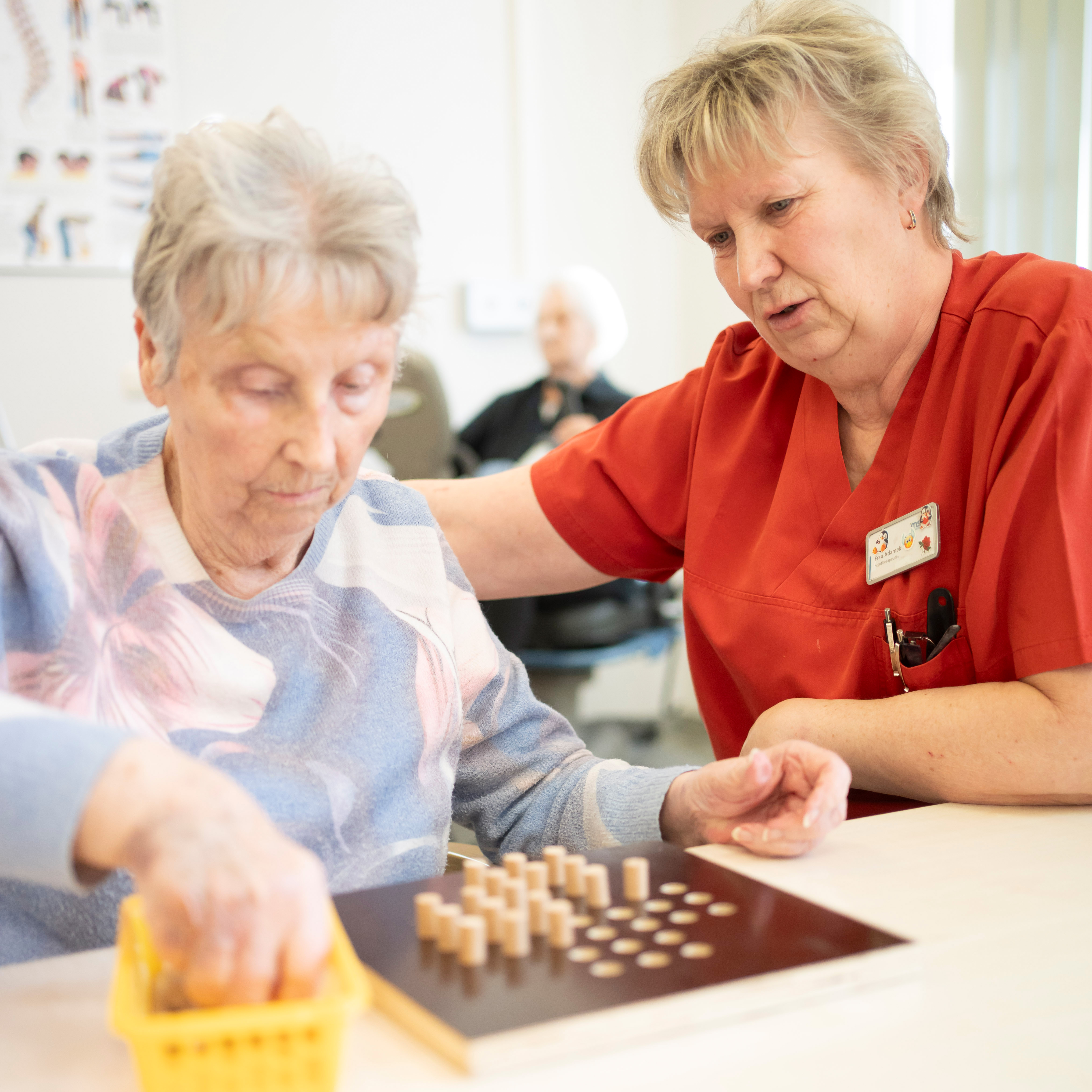 Eine Ergotherapeutin trainiert mit einem Patienten die Feinmotorik der Hände.